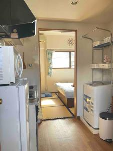 uma cozinha com um frigorífico e um quarto com uma cama em 都心の家-ダブルベットと畳み3人部屋 em Tóquio