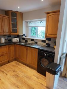 a kitchen with wooden cabinets and a washing machine at Charlton court in Radstock