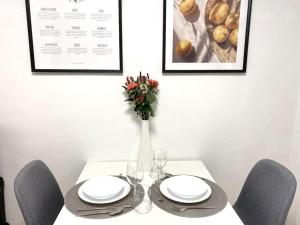 City-Apartment No 2 في ريوتلنغن: طاولة بيضاء مع كراسي و مزهرية عليها زهور