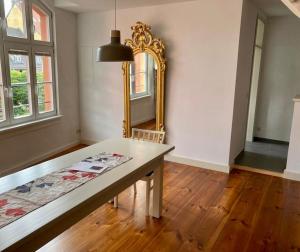 ein Esszimmer mit einem Tisch und einem Spiegel in der Unterkunft Alte Seifensiederei 3 in Stralsund