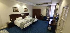 a hotel room with two beds and a television at Horus House Hotel Zamalek in Cairo
