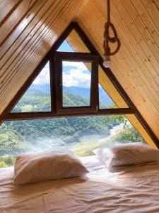 a bed in a room with a large window at Highland • Varjanisi in Batumi