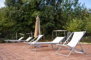 a row of lounge chairs and an umbrella at Tenuta Carbone - Con piscina e parcheggio privato in Mascali