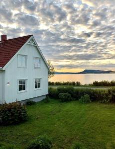 uma casa branca num campo ao lado de um corpo de água em Seaside house with stunning view 
