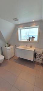 a bathroom with a tub and a sink and a window at The Fjord House in Snofugl