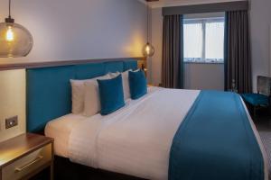 a hotel room with a large bed with blue accents at Rutland Hall Hotel in Oakham