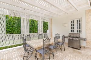 ein Esszimmer mit einem Tisch, Stühlen und einem Grill in der Unterkunft Paradise Luxury Villa with Huge Pool and Jacuzzi in Punta Cana