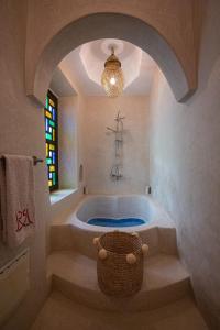 a bathroom with a tub with a window and a chandelier at Riad RIM in Marrakech