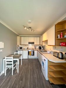 uma cozinha com armários brancos e uma mesa e cadeiras em Helens Lybster cosy cottage on NC500 em Lybster
