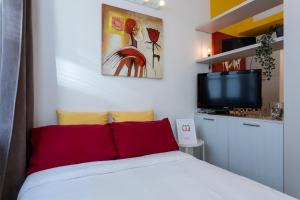 Schlafzimmer mit einem Bett mit roten Kissen und einem TV in der Unterkunft Porta Susa Studio Apartment by Wonderful Italy in Turin