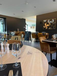 un restaurante con una mesa de madera y copas de vino en Le Presbytère de Sautour, en Sautour