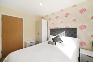 een slaapkamer met een wit bed met roze bloemen aan de muur bij Fully Furnished 2 BR Flat with Free Parking in Stoke on Trent