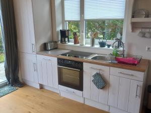 a kitchen with a stove and a sink and a window at Im Bademantel an den Strand - mit Terrasse in Eckernförde +17 photos