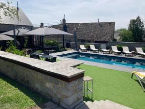 a backyard with a swimming pool with chairs and an umbrella at Le Presbytère de Sautour in Sautour