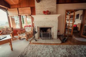 a living room with a fireplace with a couch and chairs at Pousada Marco Polo in Campos do Jordão