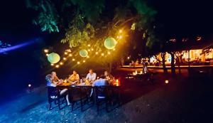 een groep mensen die 's avonds aan een eettafel zitten bij Msandile River Lodge in Kakumbi