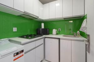 a green and white kitchen with a stove and a sink at Stone Gate Apartment #1 in Bucharest