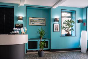 an office lobby with blue walls and plants at Hotel de Normandie in Lyon