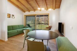 a living room with a table and a green couch at Violet a due passi da Bormio in Valdidentro