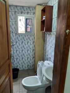 La petite salle de bains est pourvue de toilettes et d'un lavabo. dans l'établissement Signorile Jo, à Yaoundé