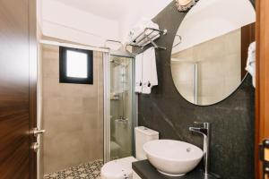 a bathroom with a sink and a toilet and a mirror at Cezar's Airport Hotel in Trakhoni +26 photos
