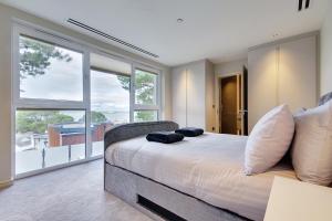 a bedroom with a large bed and large windows at Luxury 3bd penthouse with roof terrace and hot tub in Canford Cliffs
