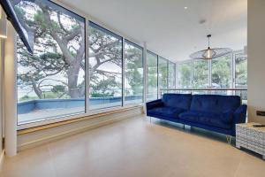 a living room with a blue couch and large windows at Luxury 3bd penthouse with roof terrace and hot tub in Canford Cliffs