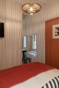 a bedroom with a bed and a chair and a chandelier at MiHotel Saint Jean in Lyon