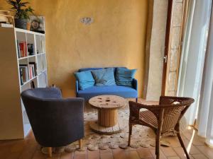 uma sala de estar com um sofá azul e cadeiras em Le Grenier à Blé em Satillieu