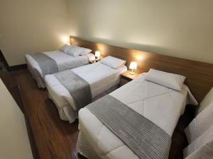 two beds in a hotel room with lights on them at Pousada Catedral in Petrópolis