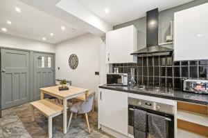 a kitchen with white cabinets and a wooden table at Stylish 4 Bed House in Nottingham - sleeps 15 in Nottingham