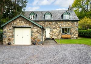 a stone house with a white garage at Cil y Fan in Llangelynin
