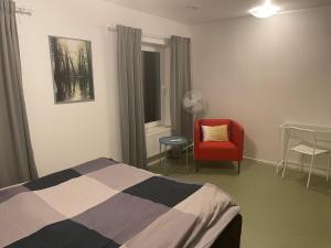 a bedroom with a bed and a red chair at Hotell Silverborgen in Sala