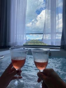 two people holding glasses of wine in front of a window at Vertentes da Mantiqueira in Santo Antônio do Pinhal