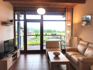 a living room with a couch and a large window at Apartmány Doky Holiday in Lipno nad Vltavou