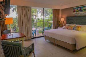 Casa Verano Beach Hotel - Adults Only في سانتا مارتا: غرفة نوم بسرير ومكتب وشرفة