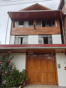 a house with a wooden garage door in front of it at Suzet House in Oxapampa