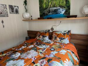 a bed with an orange comforter with a waterfall at Veluwe Park Reewold Chalet Infinity in Putten