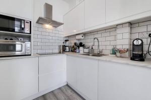 uma cozinha branca com um lavatório e um micro-ondas em Immaculately presented 1 bed em Londres