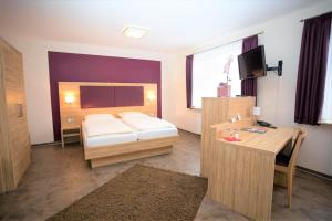 een slaapkamer met een bed en een bureau met een televisie bij IVY Hotel in Wolfsburg