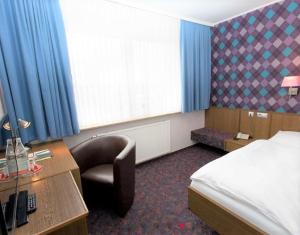 una camera d'albergo con letto e scrivania con sedia di IVY Hotel a Wolfsburg