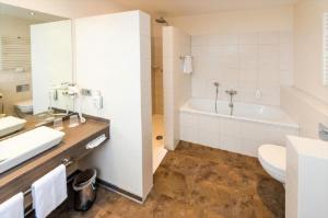 een badkamer met een bad, een wastafel en een toilet bij IVY Hotel in Wolfsburg