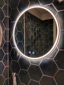 La salle de bains est pourvue d'un miroir rond sur un mur carrelé noir. dans l'établissement Charlie's Hôtel Cannes, à Cannes