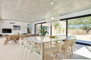 a dining room with a glass table and chairs at Exquisite Ibiza Villa Can Pegaso Grande Privileged Minimalist Style 16 guests San Juan in Sant Joan de Labritja