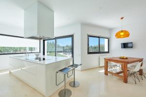 una cucina con mobili bianchi e un tavolo di legno di Exquisite Ibiza Villa Can Pegaso Grande Privileged & Minimalist Style 16 Guests San Juan a Sant Joan de Labritja