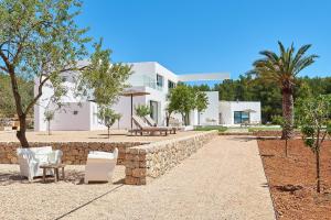a house with a stone wall and chairs and trees at Exquisite Ibiza Villa Can Pegaso Grande Privileged Minimalist Style 16 guests San Juan in Sant Joan de Labritja