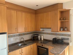 una cocina con armarios de madera y fregadero en Apartamento primera línea de Mar Enjoy the view, en Blanes