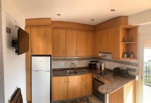 a kitchen with wooden cabinets and a white refrigerator at Apartamento primera línea de Mar Enjoy the view in Blanes