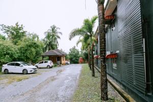 een straat met twee auto's geparkeerd naast een gebouw bij Chill Box Langkawi in Kuah