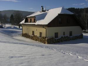 a house with a snow covered roof in the snow at Šumavské apartmány in Zdíkov